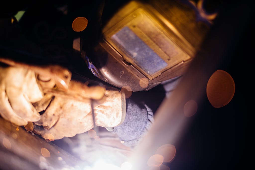Close-up of a welder working with sparks flying, highlighting industrial craftsmanship.